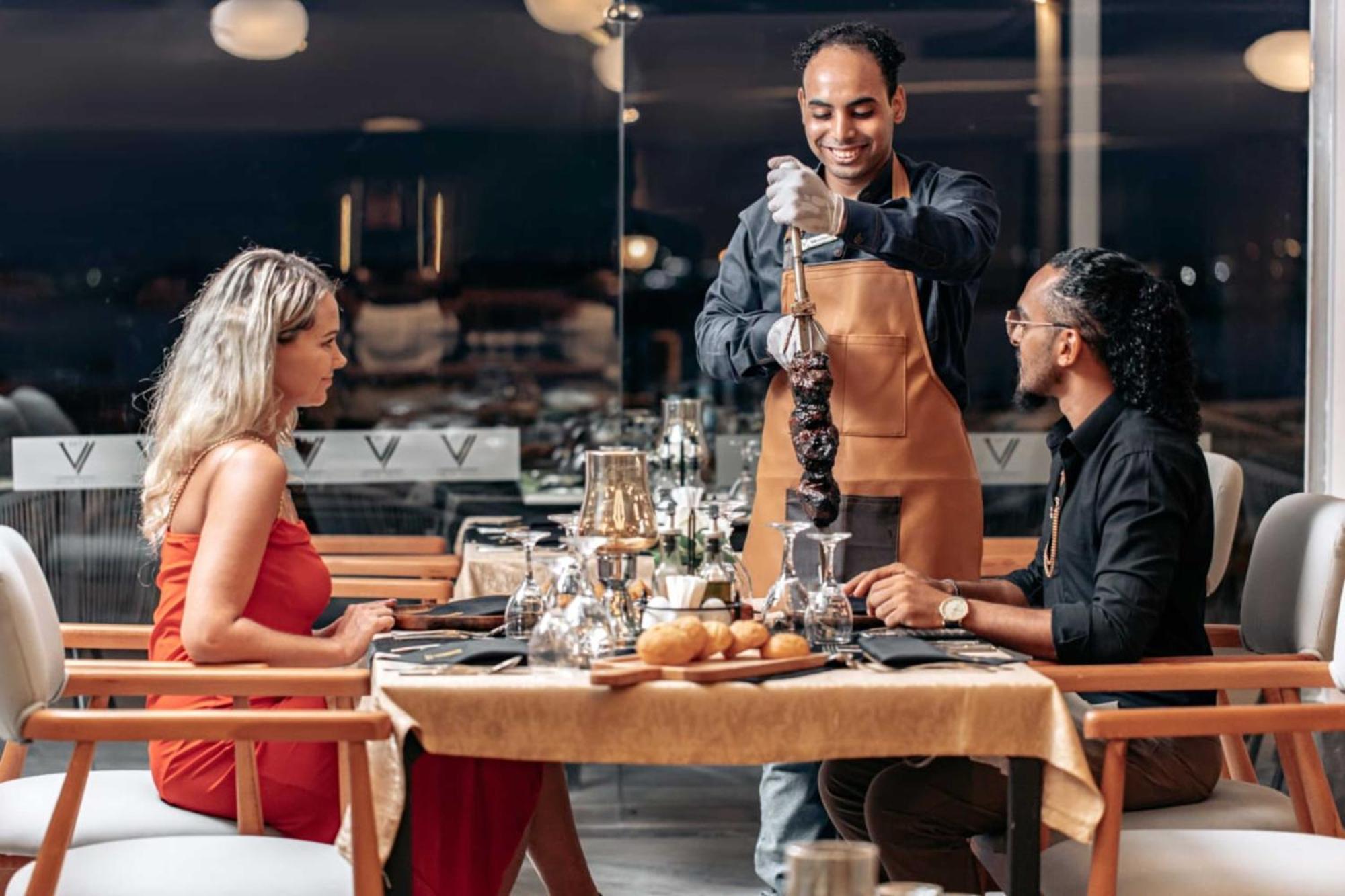 The V Luxury Resort Sahl Hasheesh Hurghada Eksteriør bilde A waiter serving a couple at a restaurant